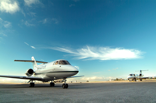 Private jets on tarmac with a clear blue sky at sunset