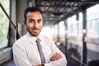 Confident businessman with crossed arms smiling in an industrial setting
