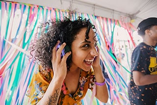 Happy woman with curly hair wearing headphones at a vibrant party.