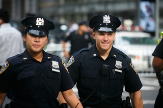 Two uniformed police officers, male and female, walking together outside in a city environment