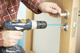 Person installing a door handle using a cordless drill