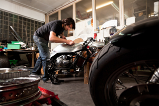 Mechanic working on custom motorcycle in a workshop