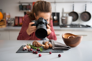 Woman photographing food arrangement with DSLR camera in kitchen setting