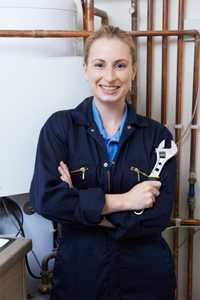 blonde female plumber in navy coveralls holding a wrench