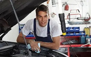 Mechanic in overalls working under the hood of a car
