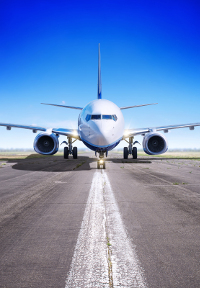 Commercial airplane centered on runway under a clear blue sky.