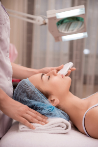 Woman receiving facial ultrasonic skin treatment in beauty clinic