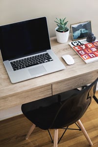 small wooden student desk with black chair and laptop