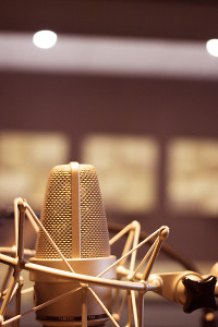 Professional studio microphone set against a blurred recording studio background with soft lighting