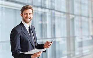 Businessman in a suit holding a document and a pen in an office building with large windows