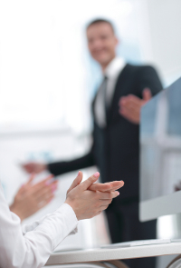 Businessman receiving applause from colleagues in an office setting.
