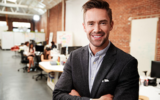 Businessman with arms crossed standing in an office environment