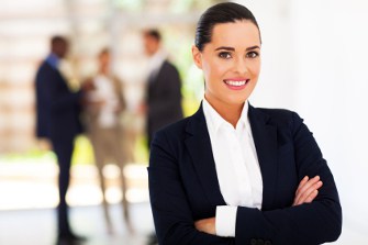 Professional woman in an office environment with colleagues in the background.