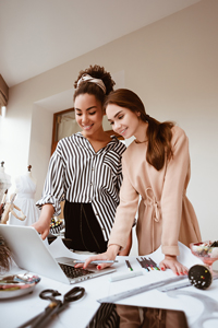 Two professional women collaborating over a laptop in a creative workspace.
