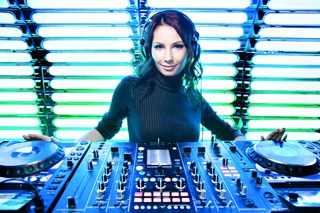 Female DJ with playing music on turntables in a club with vibrant blue LED lights background.