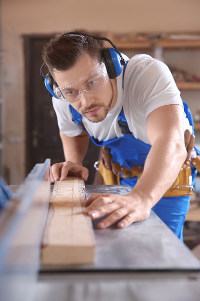 male carpenter looking down length of 2 X 4