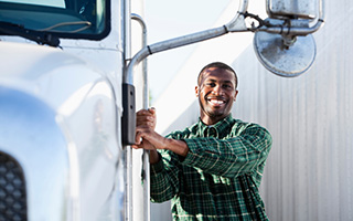 Smiling truck driver climbing into the cab of a semi-truck.