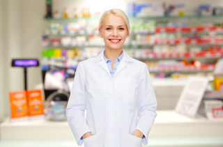 Pharmacist in white coat standing in front of pharmacy shelves filled with medications.
