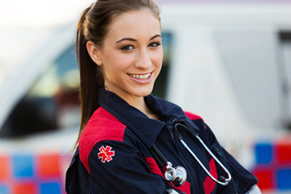 Paramedic in uniform with a stethoscope standing in front of an ambulance.