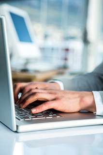 Close-up of hands typing on a laptop keyboard in an office environment