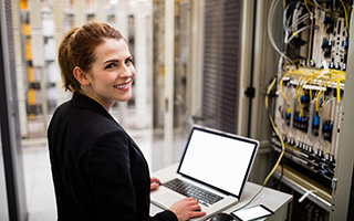 Networking technician with laptop troubleshooting server issues in a data center