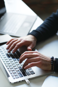 Close-up of a person's hands typing on a laptop keyboard.