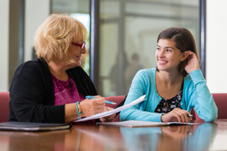 School counselor and young college student engaged in a friendly discussion in a well-lit office setting.