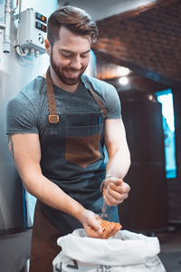Barista in apron squeezing cloth inside industrial kitchen