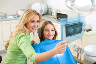 Dentist showing dental X-ray to young patient in a modern dental office