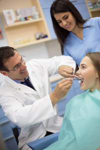 Dentist and dental assistant examining a patient's teeth in a dental clinic
