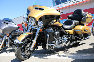 Two Harley-Davidson touring motorcycles parked outdoors, one gold and one black, under clear blue skies.