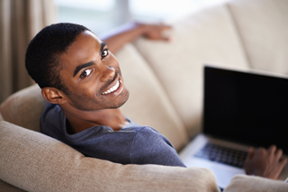 College student using laptop on sofa at home