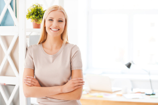 young blonde woman standing with folded arms in an office space