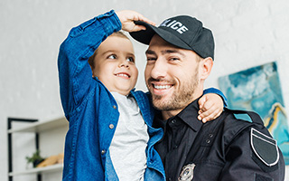 Caucasian male police officer in uniform holding a small child
