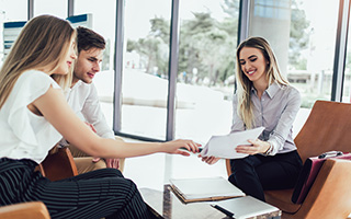 Group of business professionals shaking hands in an office setting during a meeting.