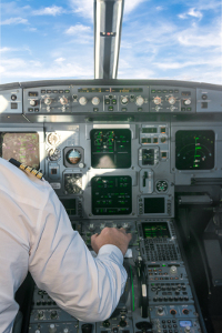 Pilot operating controls in the cockpit of an airplane with a view of instrument panels and screens