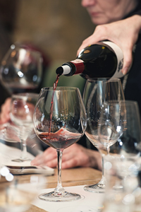Person pouring red wine into wine glasses at a tasting event