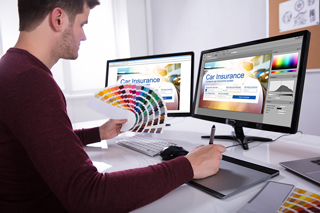 Graphic designer working on car insurance website with color swatches and a graphic tablet in an office setting