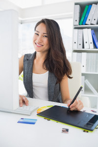 Graphic designer using digital tablet and stylus at office desk