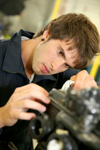 Young male mechanic attentively working on machinery in a workshop
