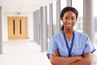 Nurse standing with arms crossed in a hospital corridor.