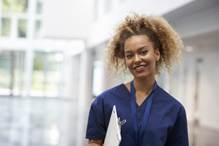 healthcare worker in navy blue scrubs holding a clipboard in hospital setting