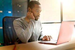 Man using laptop in sunny office setting
