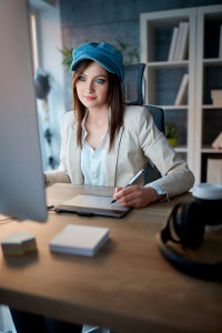Young woman in a blue hat working on game design on her computer
