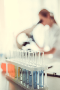 Scientist working in a laboratory with focus on a rack of test tubes containing blue liquid, background