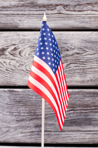 Small American flag on a stick against a wooden background