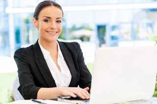 Female hospitality worker wearing a black blazer working on a laptop