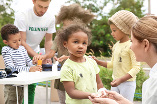 Volunteers helping children at an outdoor community service event