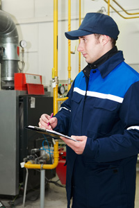 Heating technician in uniform inspecting system with clipboard in industrial facility