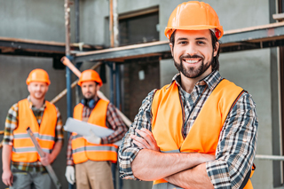 Three HVAC techs in safety gear smiling at a construction site.